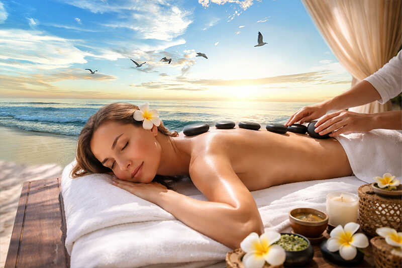 Entspannte Wellness-Szene mit weißen Orchideen, braunem Handtuch, Bimsstein und Kerze auf einem Holztisch.