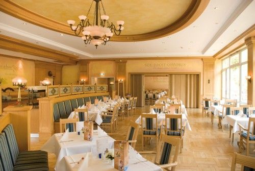 Geräumiges Restaurant mit Holzakzenten, gedeckten Tischen und dekorativen Lichtern.