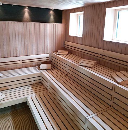 Leere Sauna mit Holzbänken und Handtüchern.