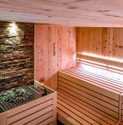 Detailansicht einer modernen Sauna mit Holzverkleidung und Steinwand.